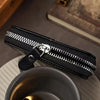 A black PU leather slim wallet with a silver clasp and visible stitching is resting on a dark surface.