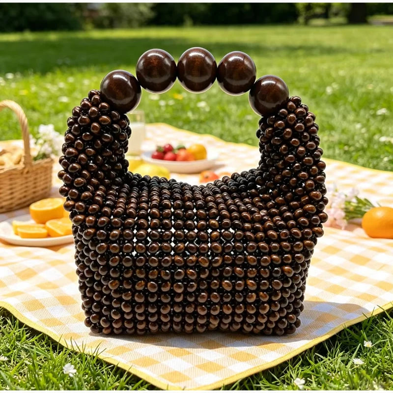 A dark brown beaded clutch bag resting on a yellow checkered cloth outdoors.