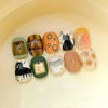 A collection of 10 cute cartoon press-on nails in various colors and designs arranged on a light background.