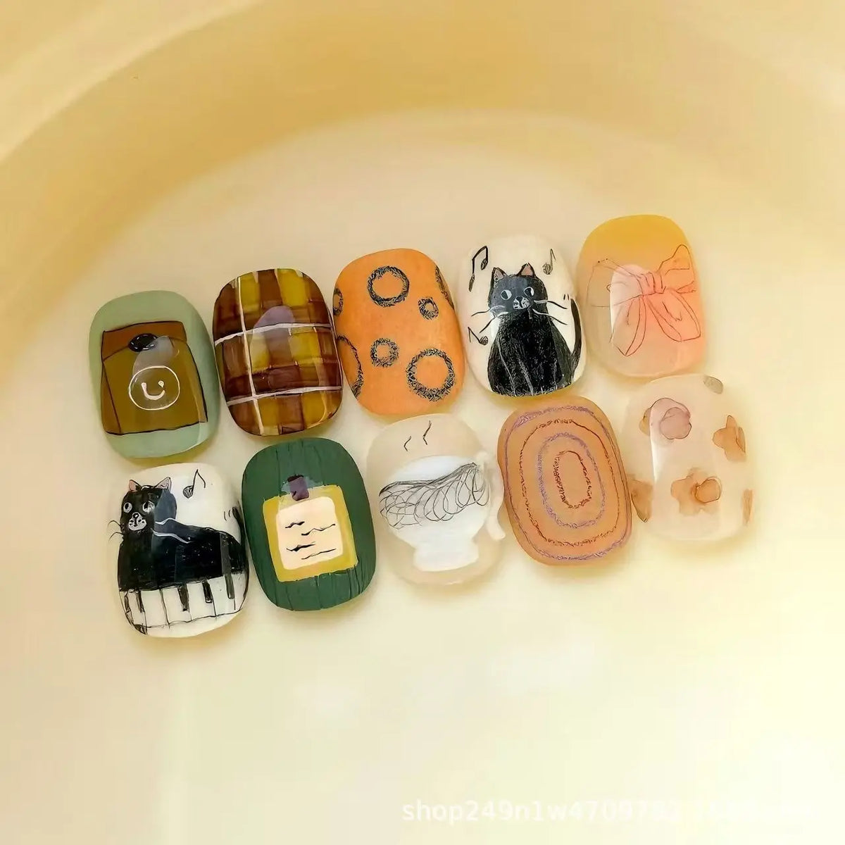 A collection of 10 cute cartoon press-on nails in various colors and designs arranged on a light background.