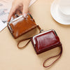 A brown vintage PU leather compact wallet with a coin pocket is shown being held by a hand on a light beige surface.