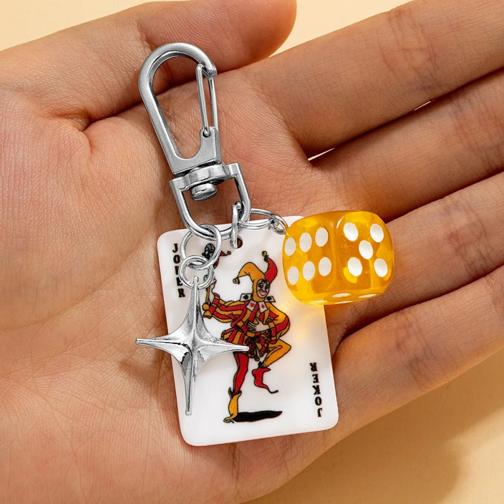 Llavero plateado con un dije de dados de póker retro, sujeto a un anillo dividido de metal.