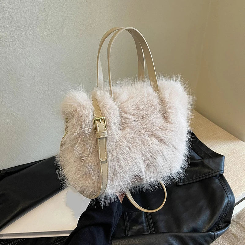 A light beige plush faux fur tote bag with a tan leather crossbody strap resting on a black leather garment.