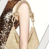 A close-up of a gold crystal rhinestone handbag with knotted chain straps against a leopard print background.