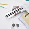 A white pencil case with black stripes featuring watercolor illustrations of faces, resting on a white surface.