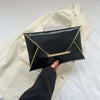 Black crocodile pattern coin purse clutch held by a hand against a light beige jacket.