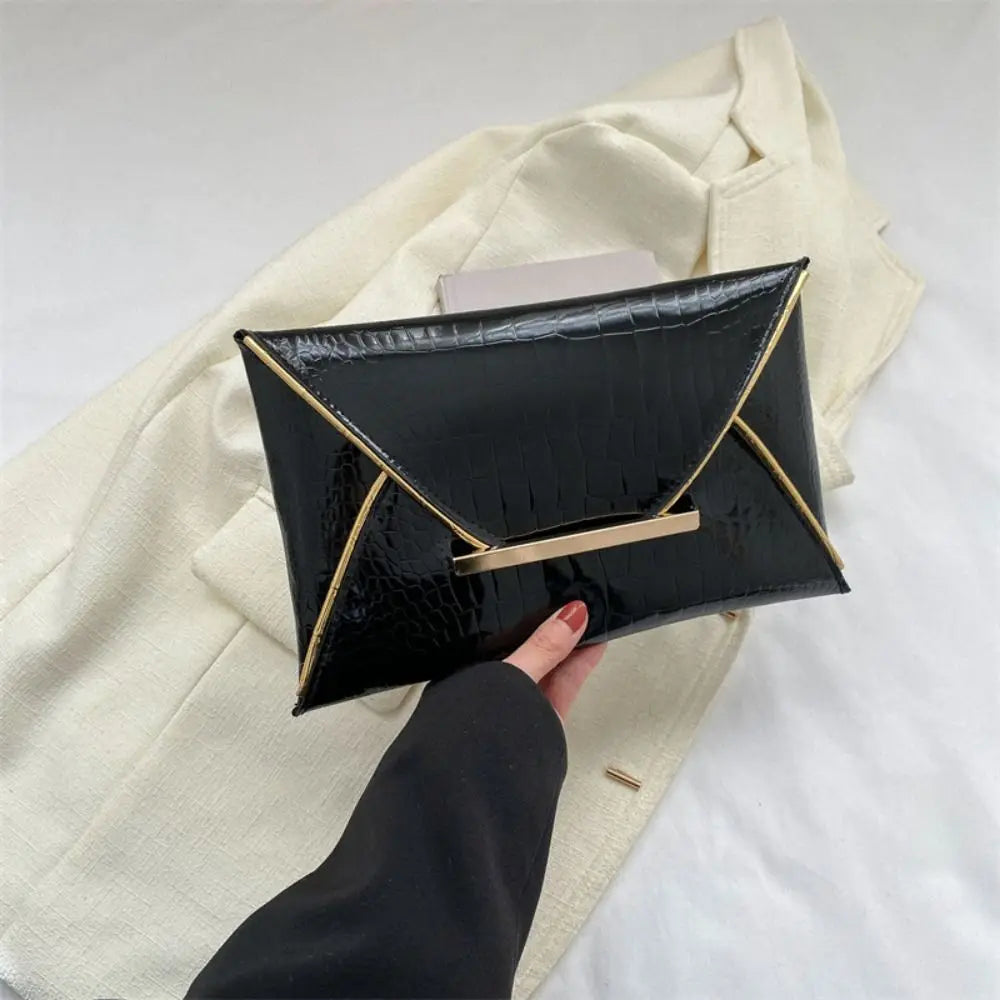 Black crocodile pattern coin purse clutch held by a hand against a light beige jacket.