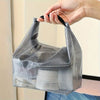 Une main tient un sac de rangement à cordon en filet gris pour le fitness et les voyages.