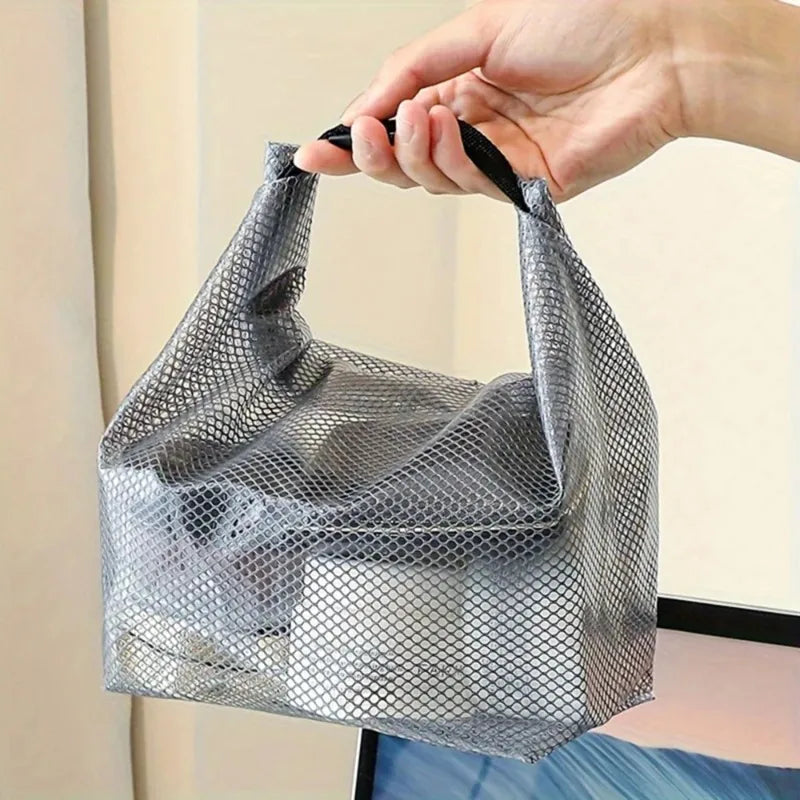 Une main tient un sac de rangement à cordon en filet gris pour le fitness et les voyages.