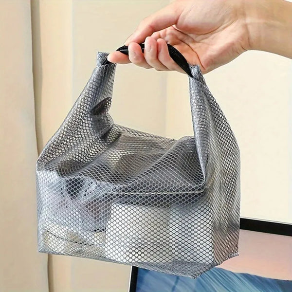 Una mano sostiene una bolsa de cordón de malla gris para fitness y viaje.