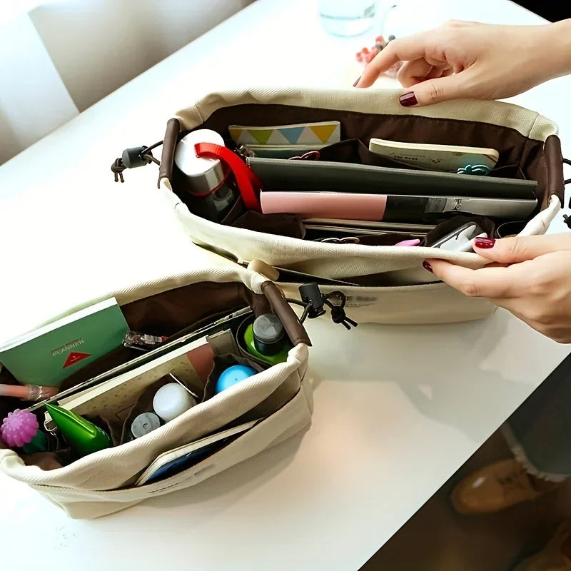 A beige drawstring canvas storage organizer bag is open, showing various pens and small items inside.