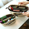 A beige drawstring canvas storage organizer bag is open, showing various pens and small items inside.