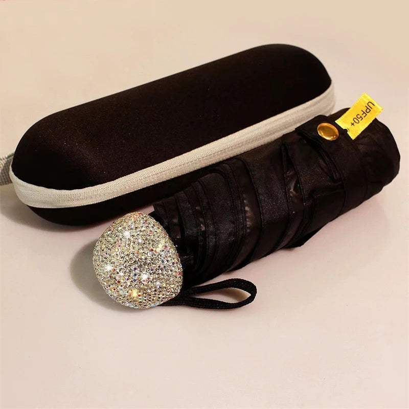 A black compact umbrella with a rhinestone sphere handle and UV protection tag.