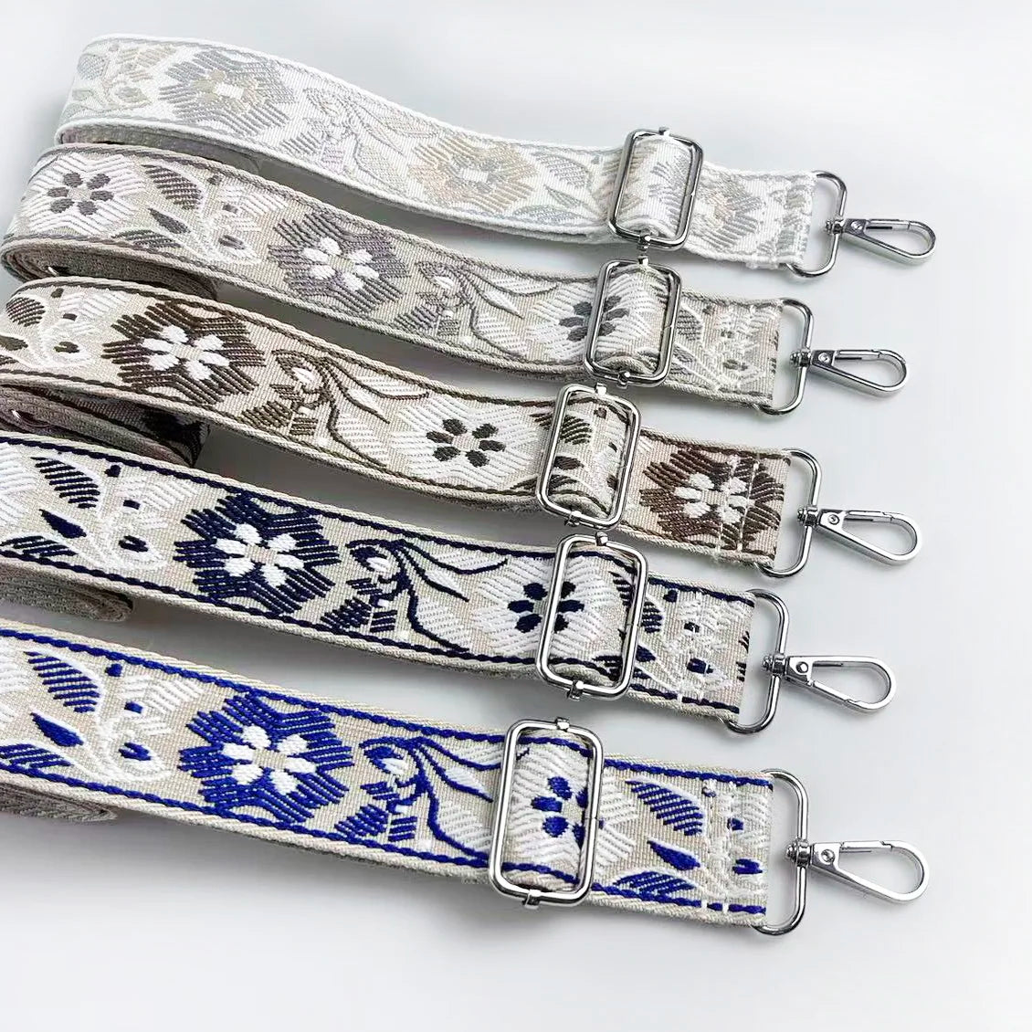 A set of beige and white floral patterned adjustable straps for a crossbody bag.