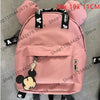 Mochila de peluche rosa con forma de ratón pato y detalles negros y un bolsillo frontal.