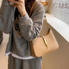A woman holds a tan PU leather hobo shoulder bag with a gold chain against a light background.