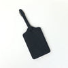 A black PU leather luggage tag with a leather strap attached.