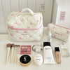 Sac de rangement cosmétique en duvet blanc avec motif nœud, entouré de produits et outils de beauté.
