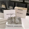 A crystal-embellished evening clutch with a chain displayed in a white box and on a marble surface.