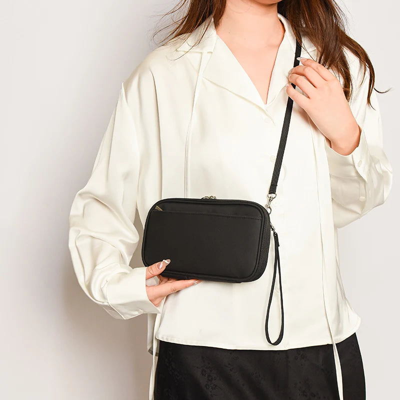 A woman wearing a white shirt holds a black multi-functional passport and document organizer.