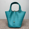 A teal genuine leather bucket bag with a gold-toned clasp and leather trim, shown from the front.