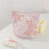 A pink cosmetic organizer bag with a large bow knot detail is shown on a white surface.