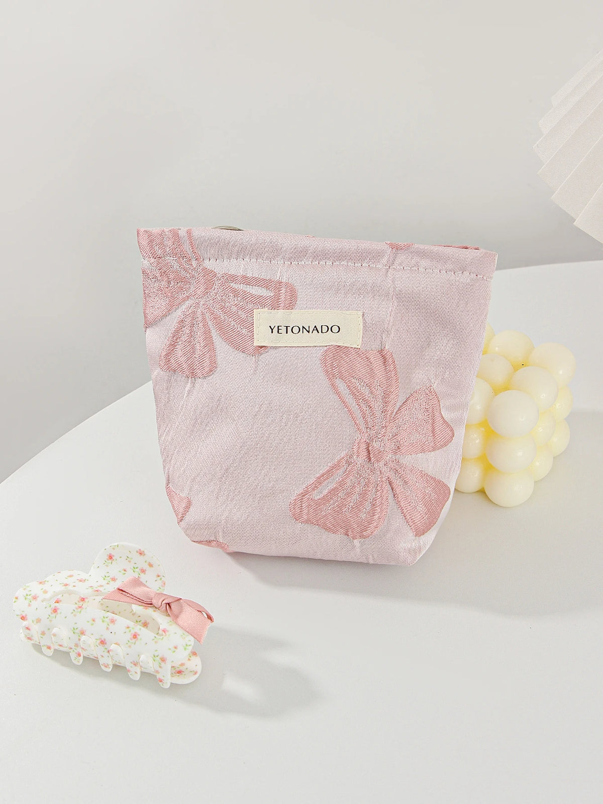 A pink cosmetic organizer bag with a large bow knot detail is shown on a white surface.