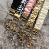 Präsentation verschiedener gemusterter Stoff-Lanyards mit goldenen Schlüsselanhängern und Metallverschlüssen.