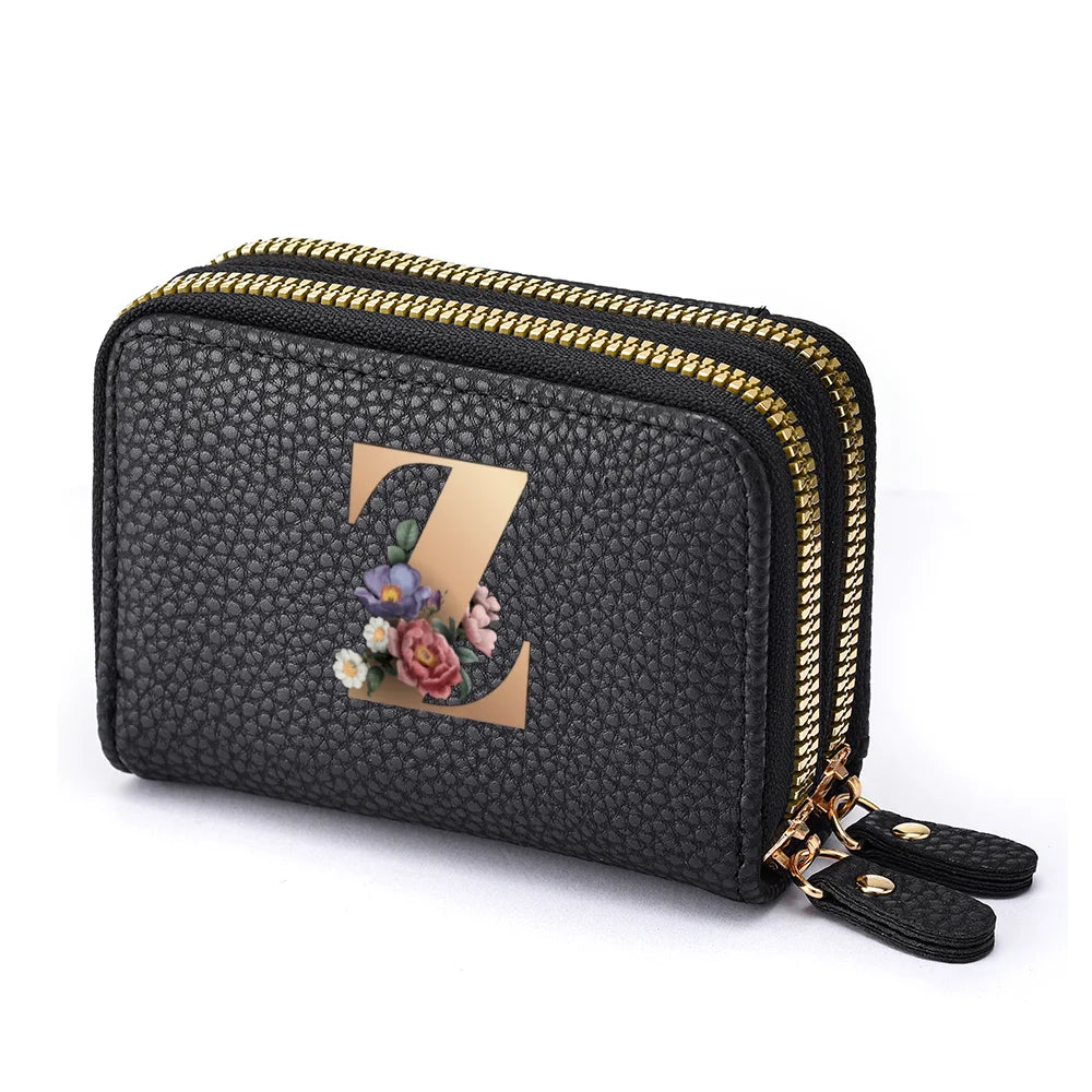 Black mini wallet with a gold zipper and a floral letter print on the front