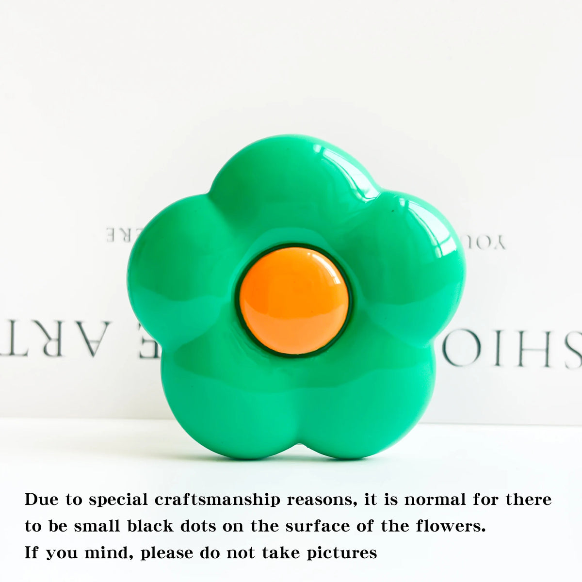 A bright green flower-shaped phone grip ring stand with small black dots on the surface.