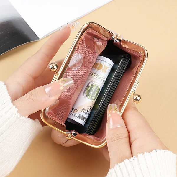 A hand holds a retro candy-colored coin purse with a gold buckle, inside which is a rolled-up banknote.