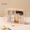 A clear plastic toiletry bag with a zipper holds several glass bottles and tubes of skincare products.