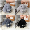 A set of cute plush rabbit bag charms in light gray and black, shown with gold keyrings.