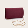 A deep burgundy velvet evening clutch with a gold chain strap lying on a light background.