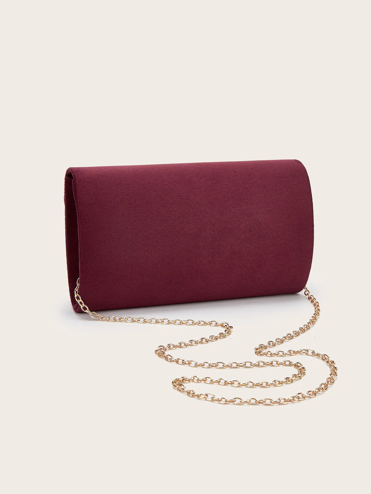A deep burgundy velvet evening clutch with a gold chain strap lying on a light background.