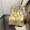 A gold crystal-embellished evening clutch with a chain is displayed against a gray suit jacket.