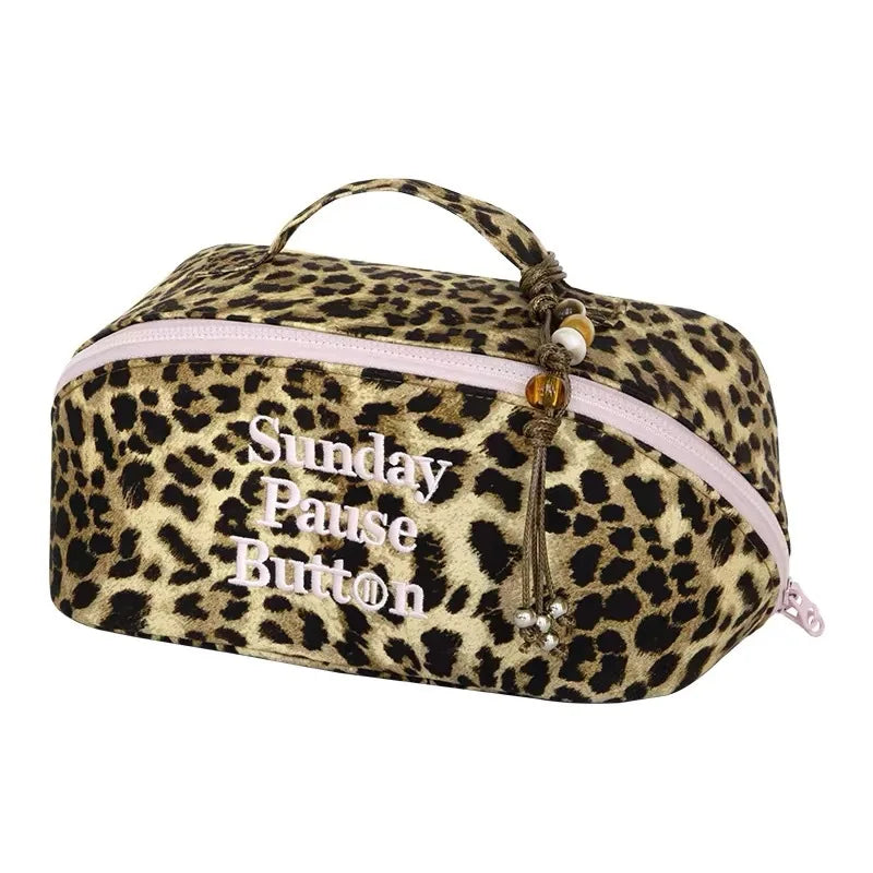 Bolso de maquillaje para viajar con estampado de leopardo y cierre de cremallera y botón rosa.
