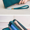 A teal vintage double-zipper wallet is shown open, displaying various cards and cash inside.