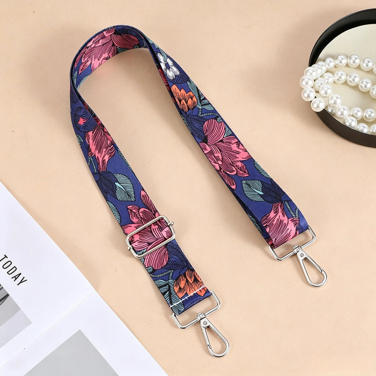 A floral patterned nylon crossbody bag strap with a silver metal buckle displayed on a light background.