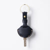 A black genuine leather key fob cover with a gold-colored ring and a metal key attached.