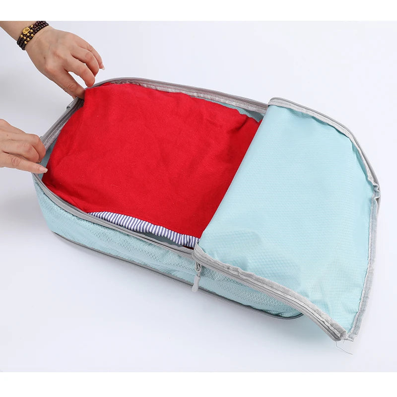 A vertical travel organizer bag is shown open, revealing two compartments: one red and one light blue.