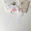 A pearl keychain featuring a bowknot design with white lace and pink beads on a white ribbon.