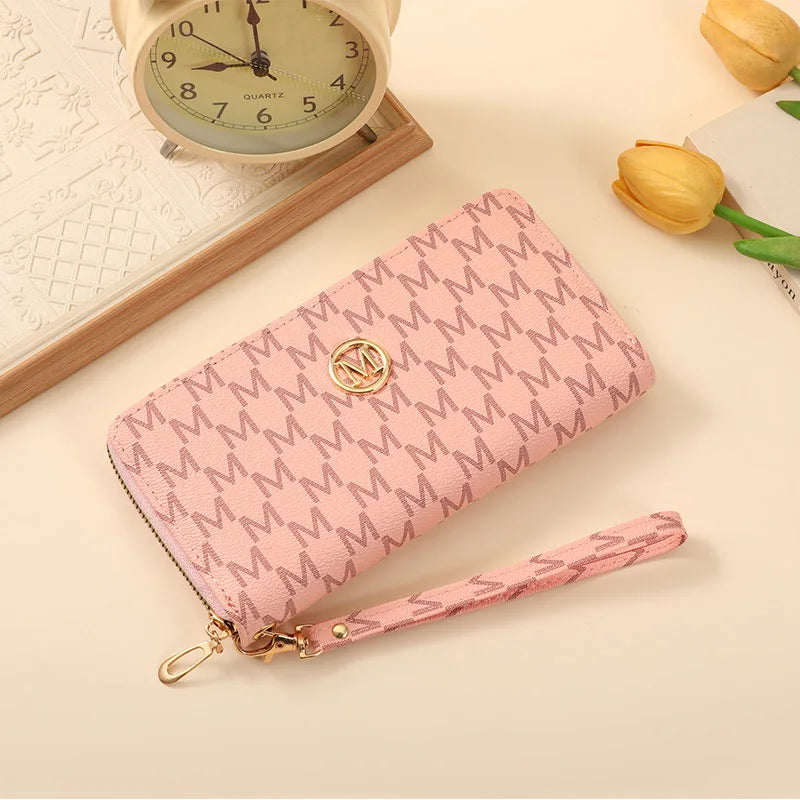 A pink patterned zipper wallet lying next to a vintage-style clock and a yellow tulip.