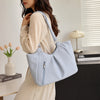 A light blue retro polka dot shoulder tote bag carried by a woman in a cream-colored dress.