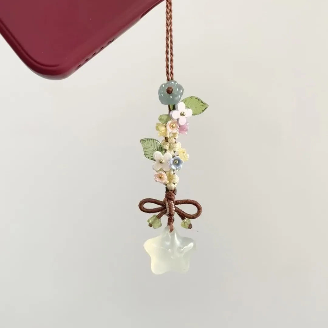 Pendentif suspendu avec de petites fleurs colorées et une goutte de verre transparent sur un fil brun.