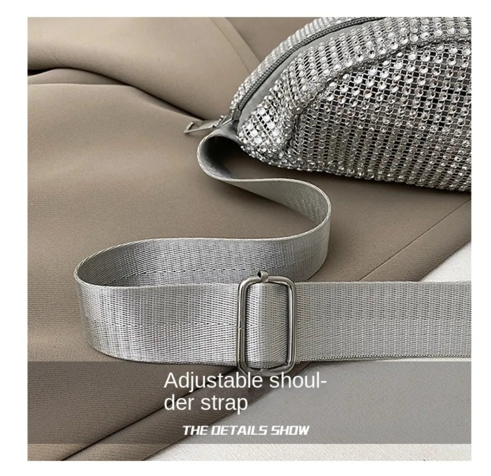 Silver rhinestone-embellished crossbody bag with a gray adjustable strap shown on a beige fabric.
