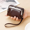 A brown vintage PU leather compact wallet with a silver zipper and leather strap is held in a person's hand.