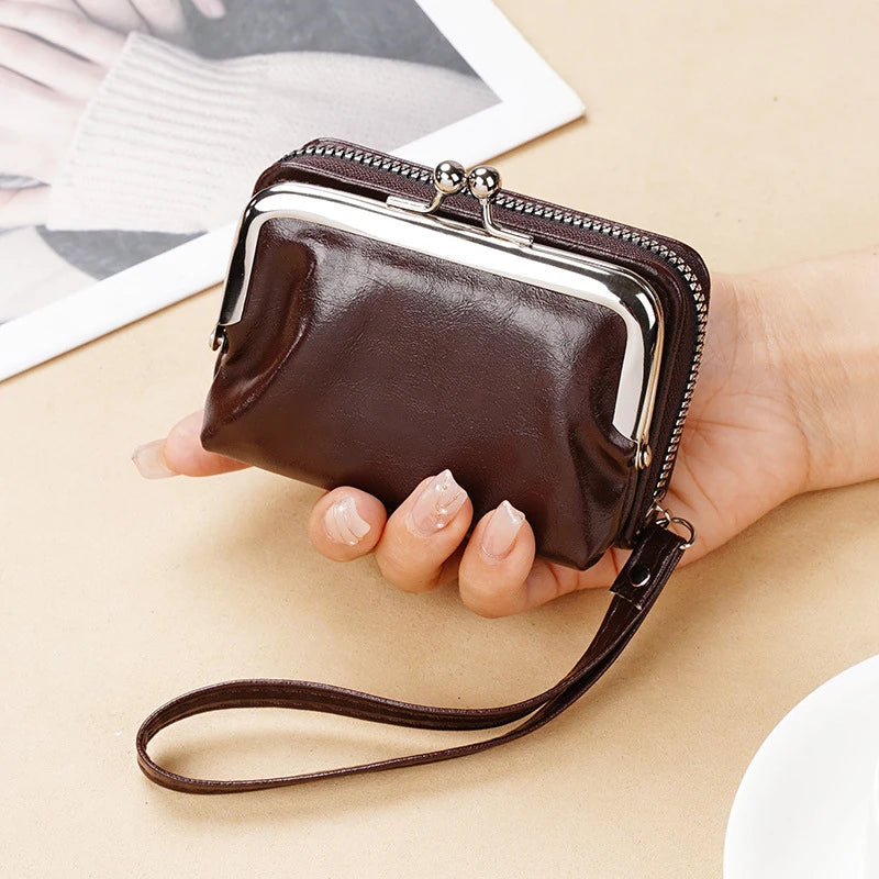 A brown vintage PU leather compact wallet with a silver zipper and leather strap is held in a person's hand.