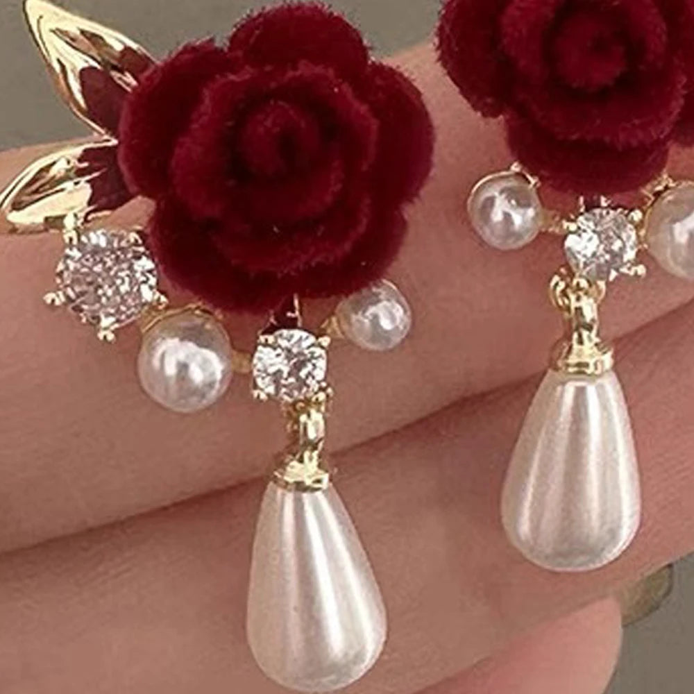 Gold-toned velvet rose and pearl stud earrings with a teardrop dangle.