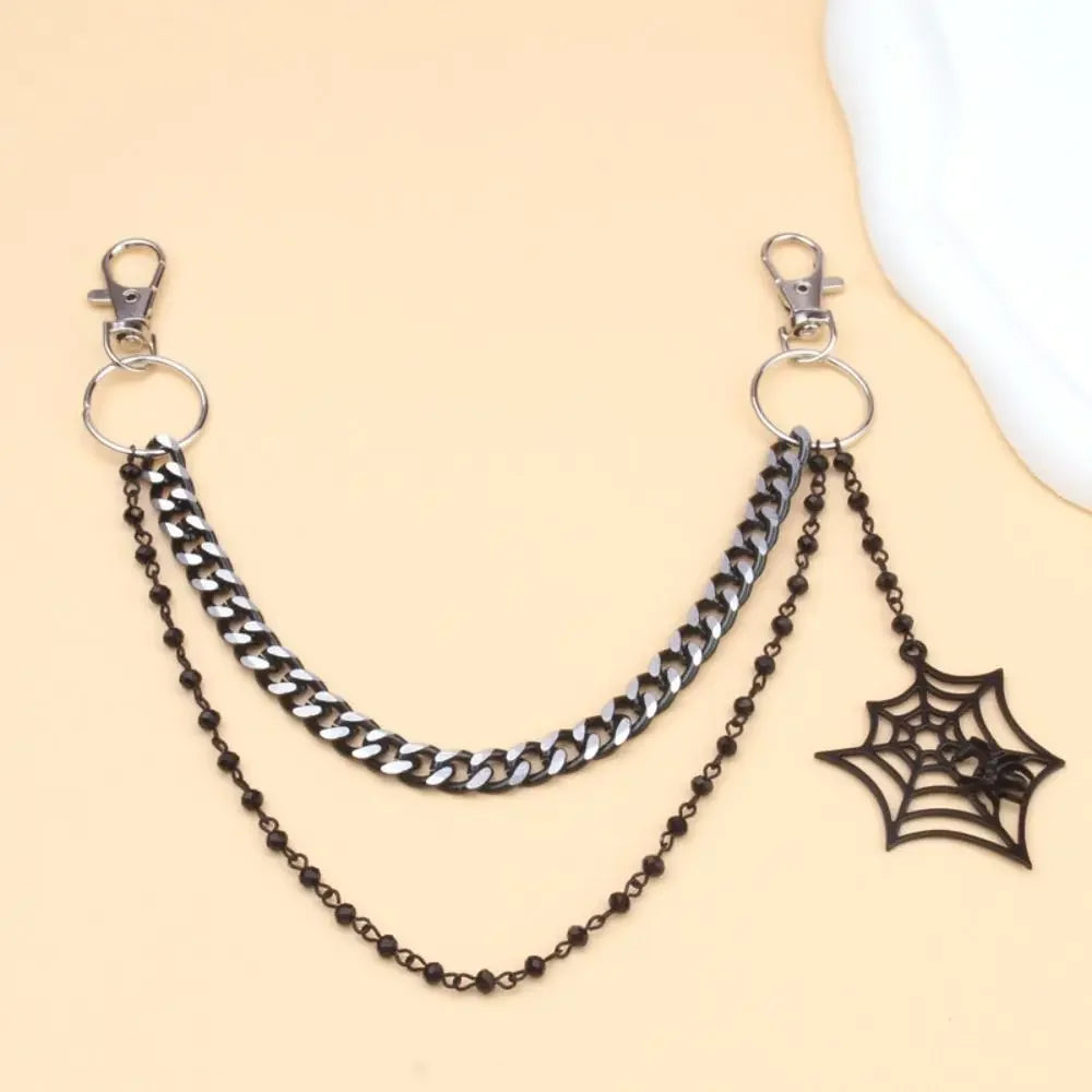 Silver metal purse chain strap with a black spider pendant displayed on a beige background